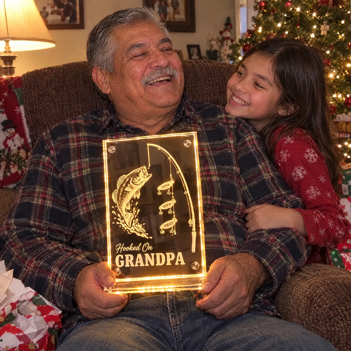 Granddaughter hugs grandpa holding lit Hooked On GRANDPA mirror at Christmas
