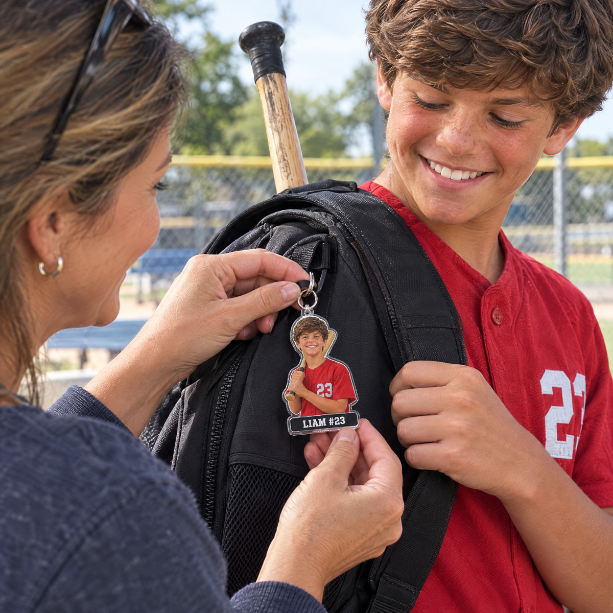 Mom attaches the baseball bag tag keychain to her son's bat bag at the field
