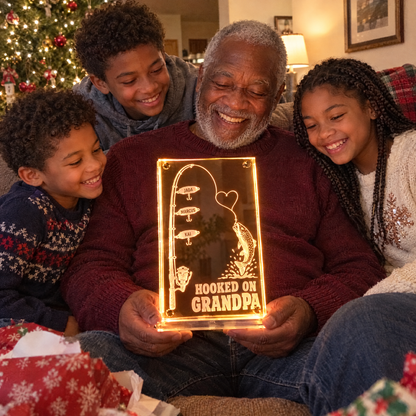 Grandkids gather around grandpa holding lit HOOKED ON GRANDPA mirror at Christmas