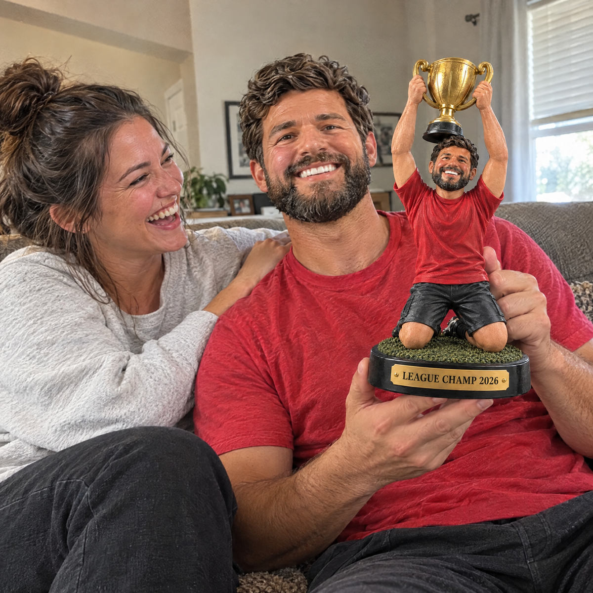 His wife laughs as he shows off the fantasy football champion trophy at home